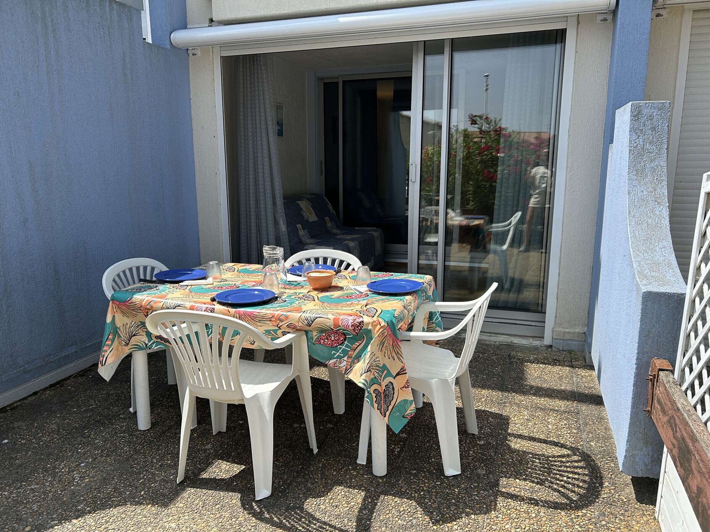 Een terras tafel met stoelen, een tafelkleed en een schaal.