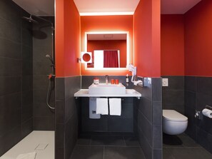 A modern bathroom with a shower, sink, and toilet.