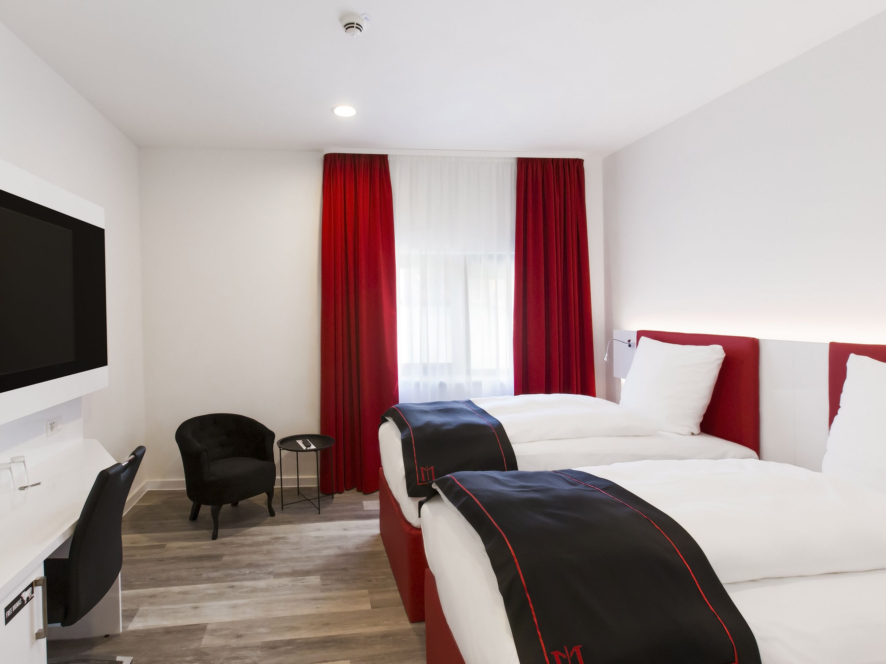 A hotel room with a bed, a desk, a chair, and a TV.