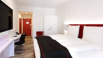 Camera d'albergo moderna con un letto grande, una scrivania e un armadio.