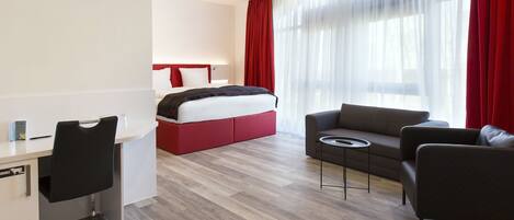 Una habitación de hotel moderna con cama, sofá, escritorio y una silla.