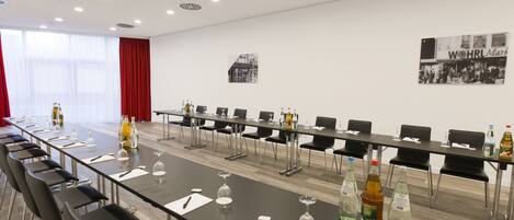 A conference room with a long table, chairs, and various beverages.