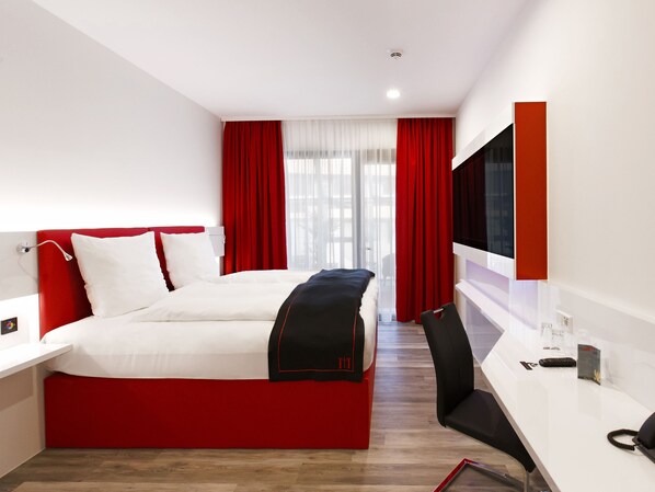 Habitació d'hotel moderna amb llit, escriptori, cadira i televisió.