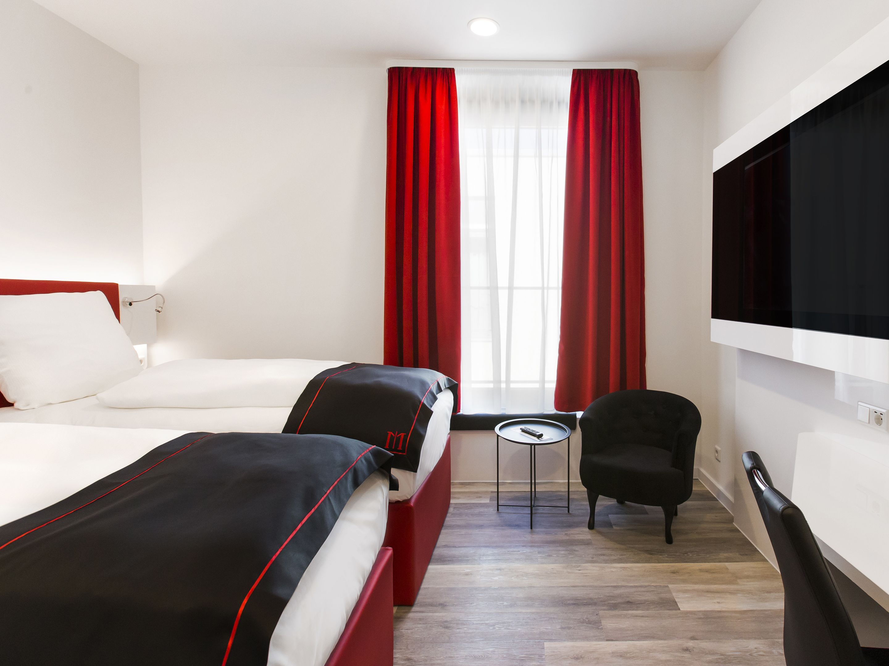 Habitación de hotel con dos camas, un televisor, una mesita y una silla.