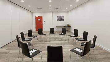 A conference room with a circular arrangement of chairs, a red door, a table with bottles, and a poster on the wall.