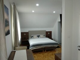 Un dormitorio con cama, mesitas de noche, un escritorio y una silla.