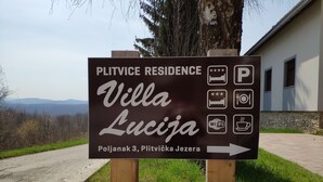 A sign for Plitvice Residence Villa Lucia, indicating amenities like parking, Wi-Fi, and a restaurant.