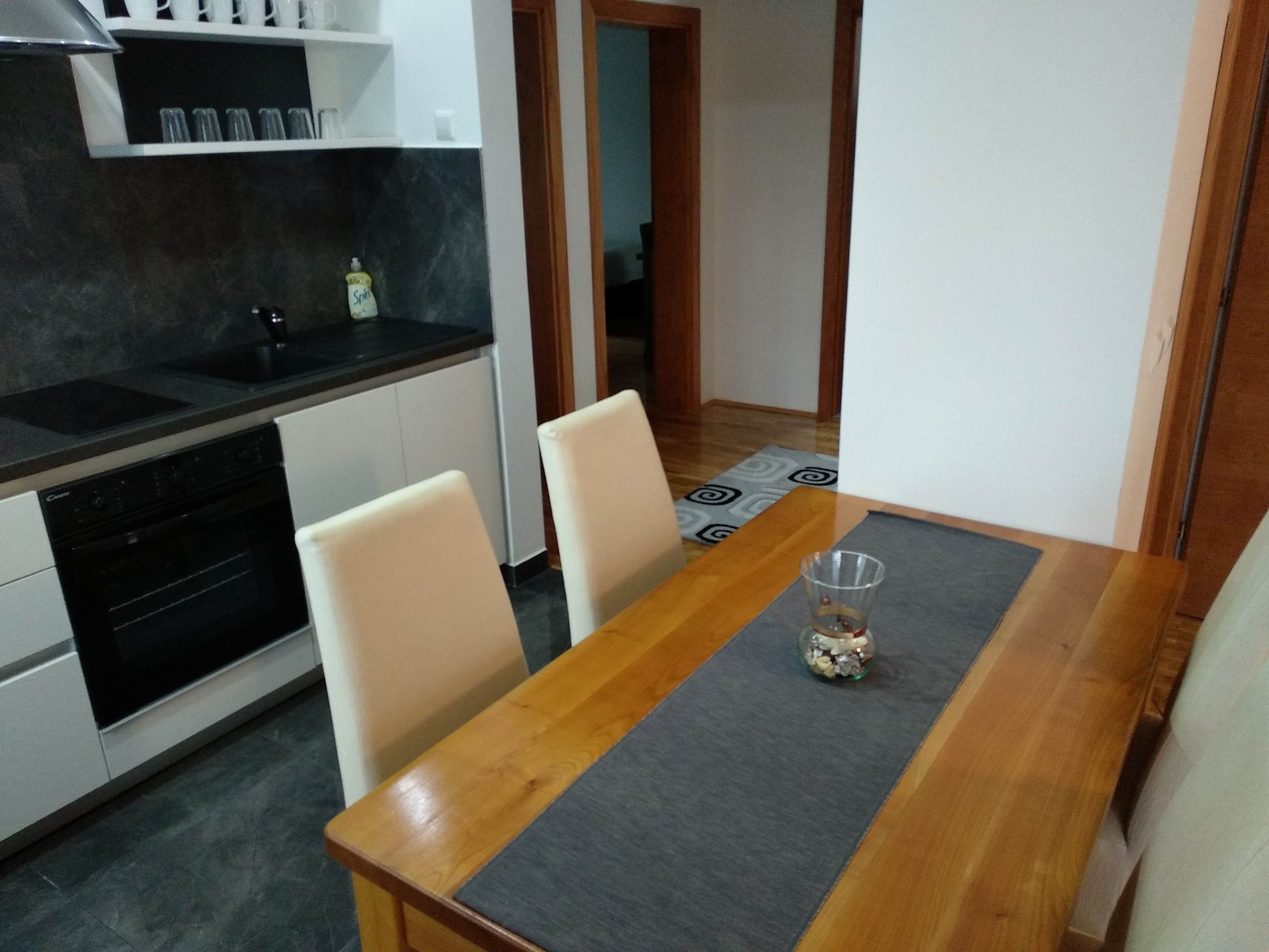 A compact kitchen with a dining table, chairs, and a small cabinet.
