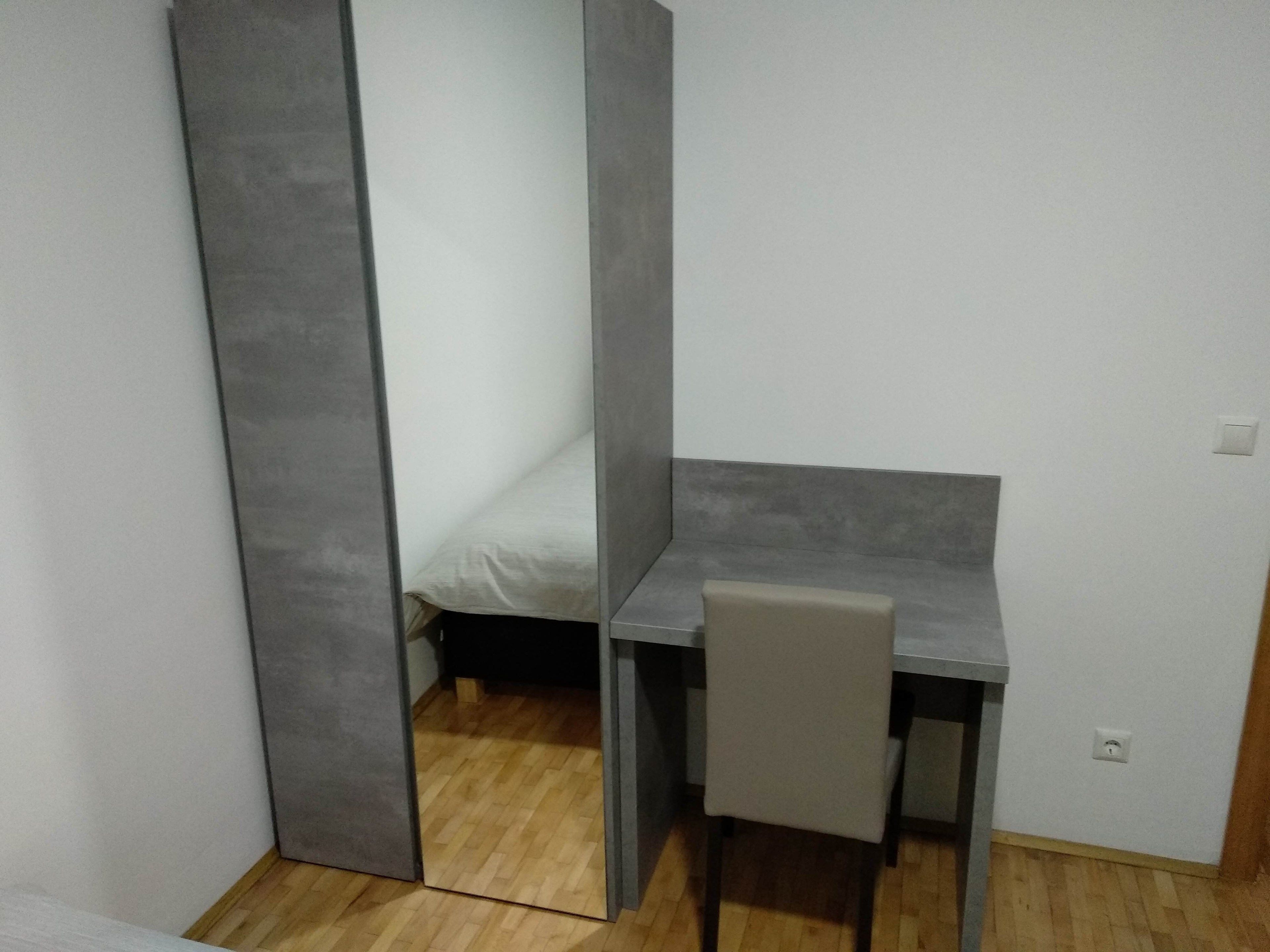 Una habitación pequeña y funcional con cama, escritorio y silla.