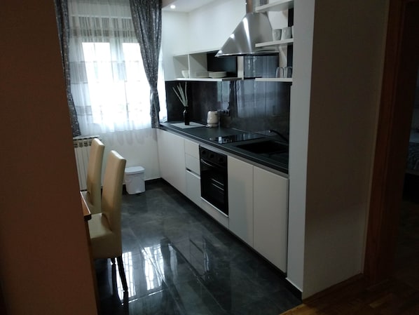 A modern kitchen with white cabinets, a black countertop, and stainless steel appliances. - Plitvice Residence Villa Lucija (Plitvicka Jezera)