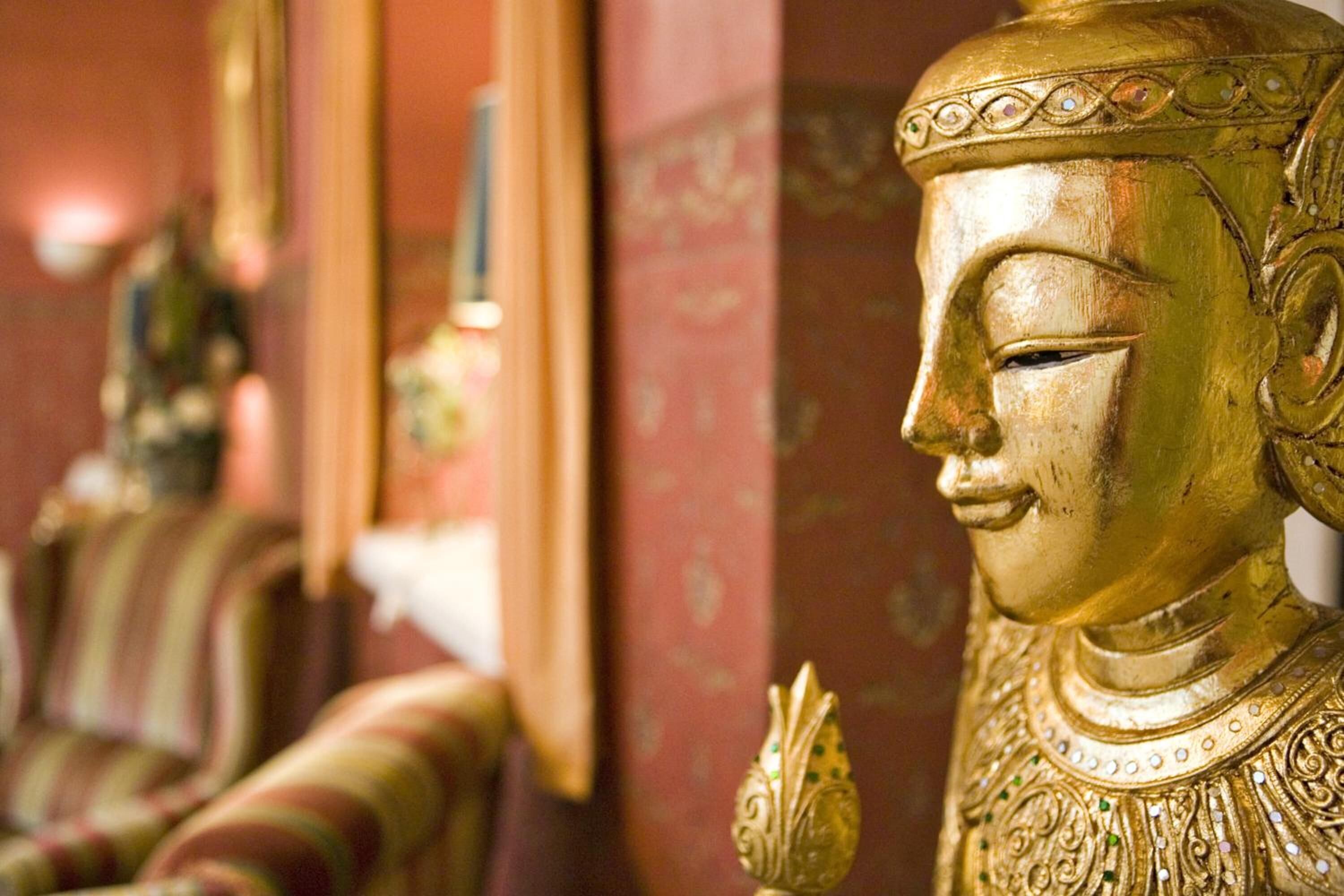 A golden Buddha statue with intricate designs and a decorative object beside it.
