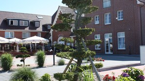 En hotellinnergård med en välskött trädgård, inklusive olika buskar och ett bonsaiträd.