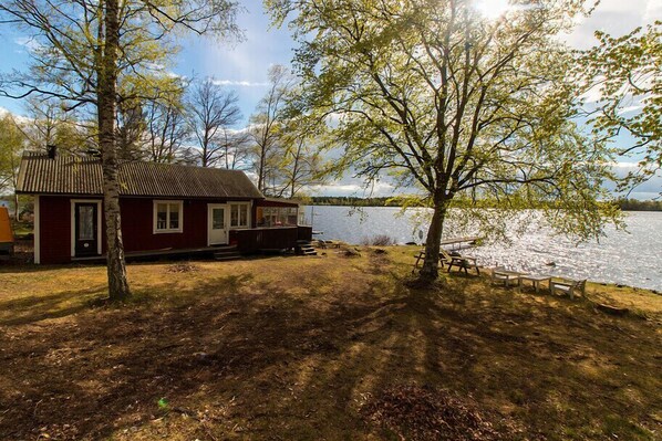 A red cabin by a lake with a dock and picnic tables. - Holiday Home Fålaboda - 6 people (Urshult)