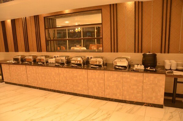 A buffet setup with various food containers and utensils. - Hotel Placid (Prayagraj)