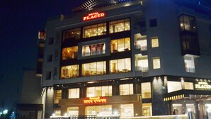 A multi-story hotel with illuminated signage, balconies, and a prominent entrance. - Hotel Placid (Prayagraj)