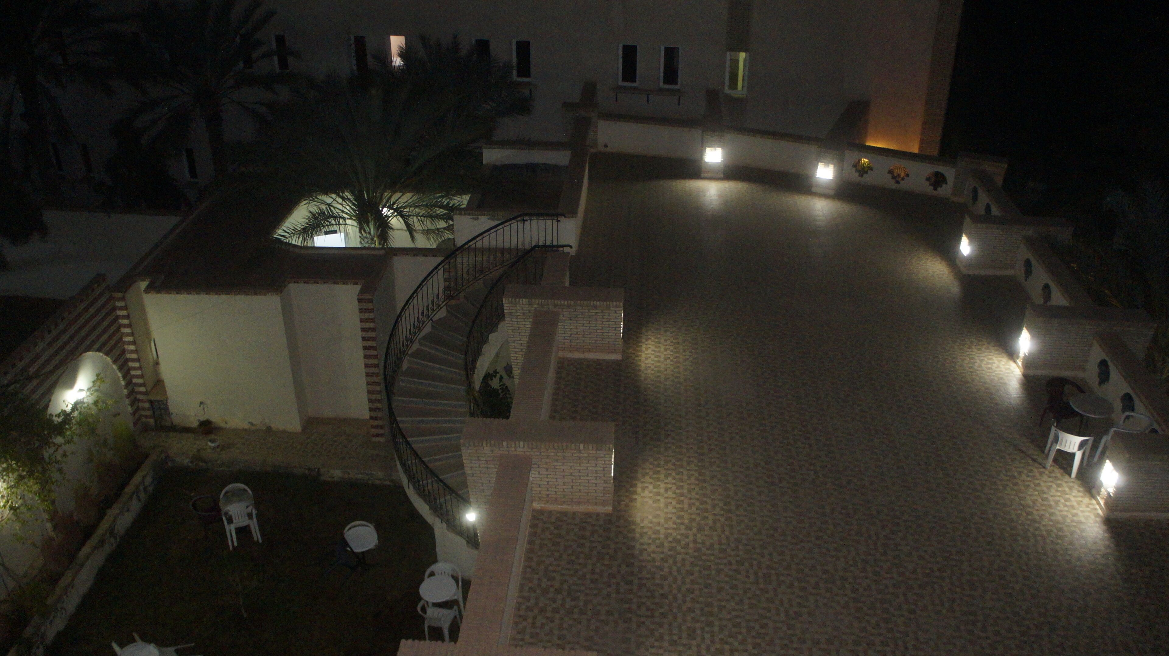 A courtyard with a central staircase, outdoor seating, and a palm tree.
