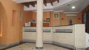 A lobby with a central column, tiled walls, and a reception desk. - Résidence El Arich (Tozeur)