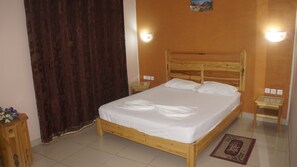 A neatly made bed with white linens in a room with wooden flooring, two bedside tables, and a wall-mounted light fixture. - Résidence El Arich (Tozeur)