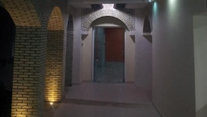 A corridor with brick arches, a wooden ceiling, and a door at the end. - Résidence El Arich (Tozeur)