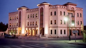 A large, multi-story building with a symmetrical facade, featuring arched windows and decorative elements. - Résidence El Arich (Tozeur)