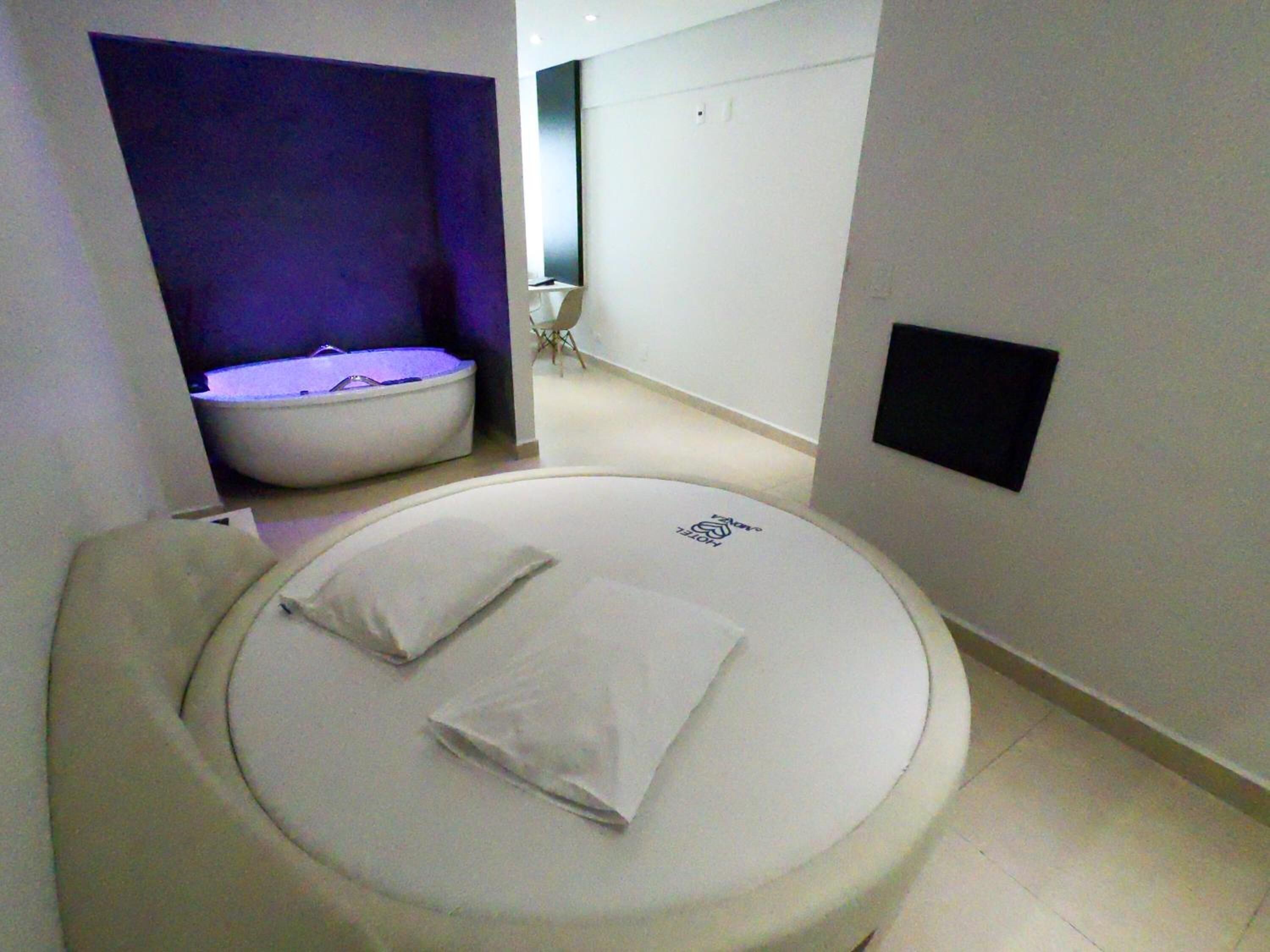 Quarto de hotel moderno com uma cama redonda, um espaço de estar pequeno e um design minimalista.