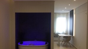 Een moderne badkamer met een vrijstaand bad, een klein tafeltje en een stoel.