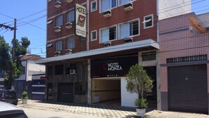 Hotel genaamd "HOTEL MONZA" met een bord, een parkeerplaats en een hekwerk.