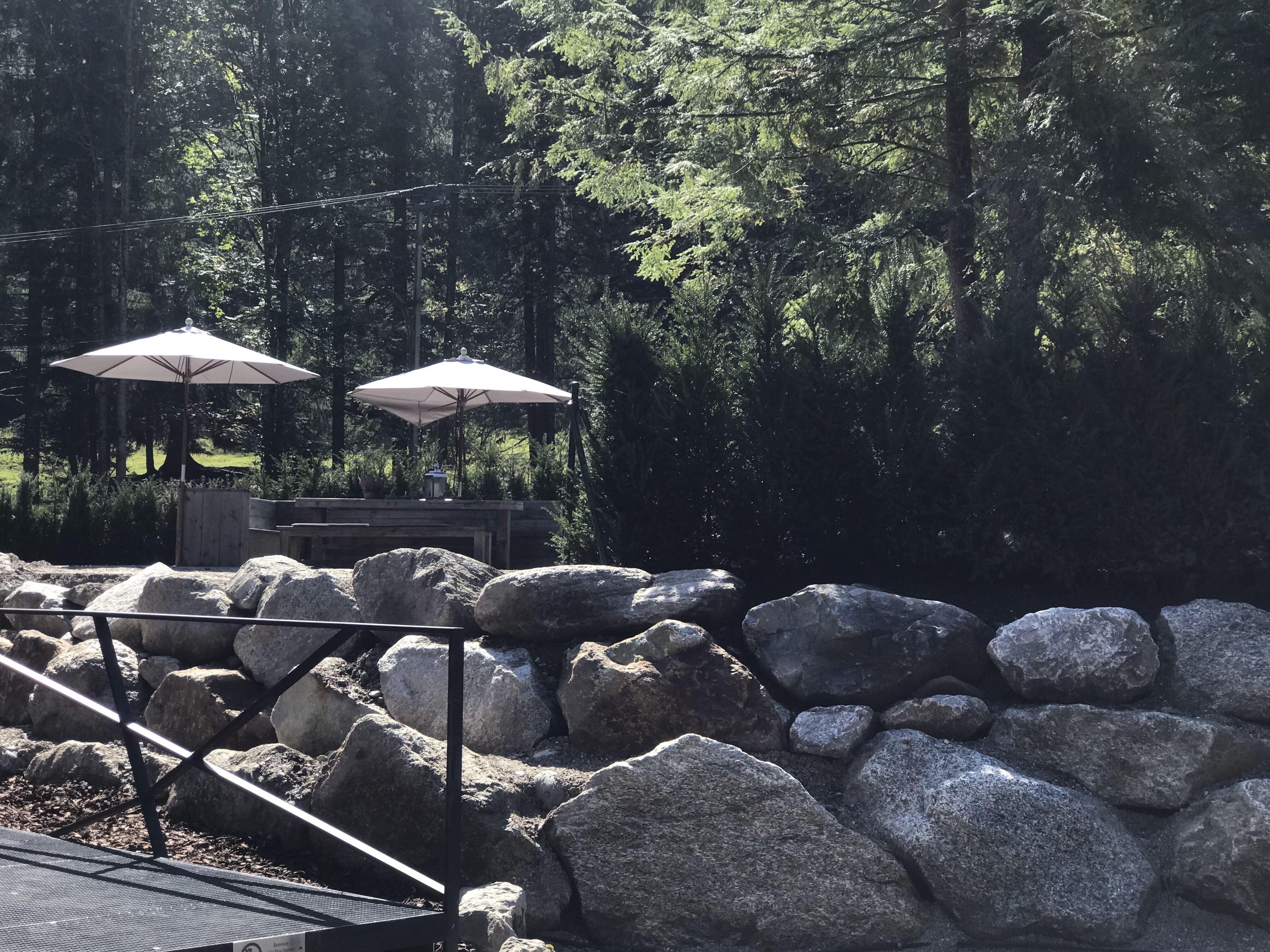 A stone patio with large rocks and two white umbrellas.
