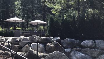 A stone patio with large rocks and two white umbrellas.