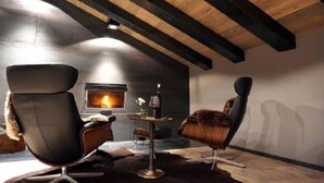Una habitación acogedora con chimenea, dos sillas modernas y una mesita.