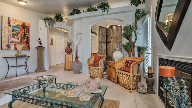A spacious living room with a glass coffee table, wicker furniture, and a fireplace.
