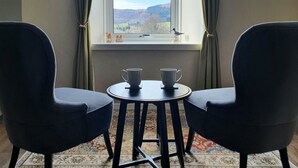 A room with two chairs, a small table, and a window with a view of a landscape. - Beautiful views, walking distance to town (Pitlochry)