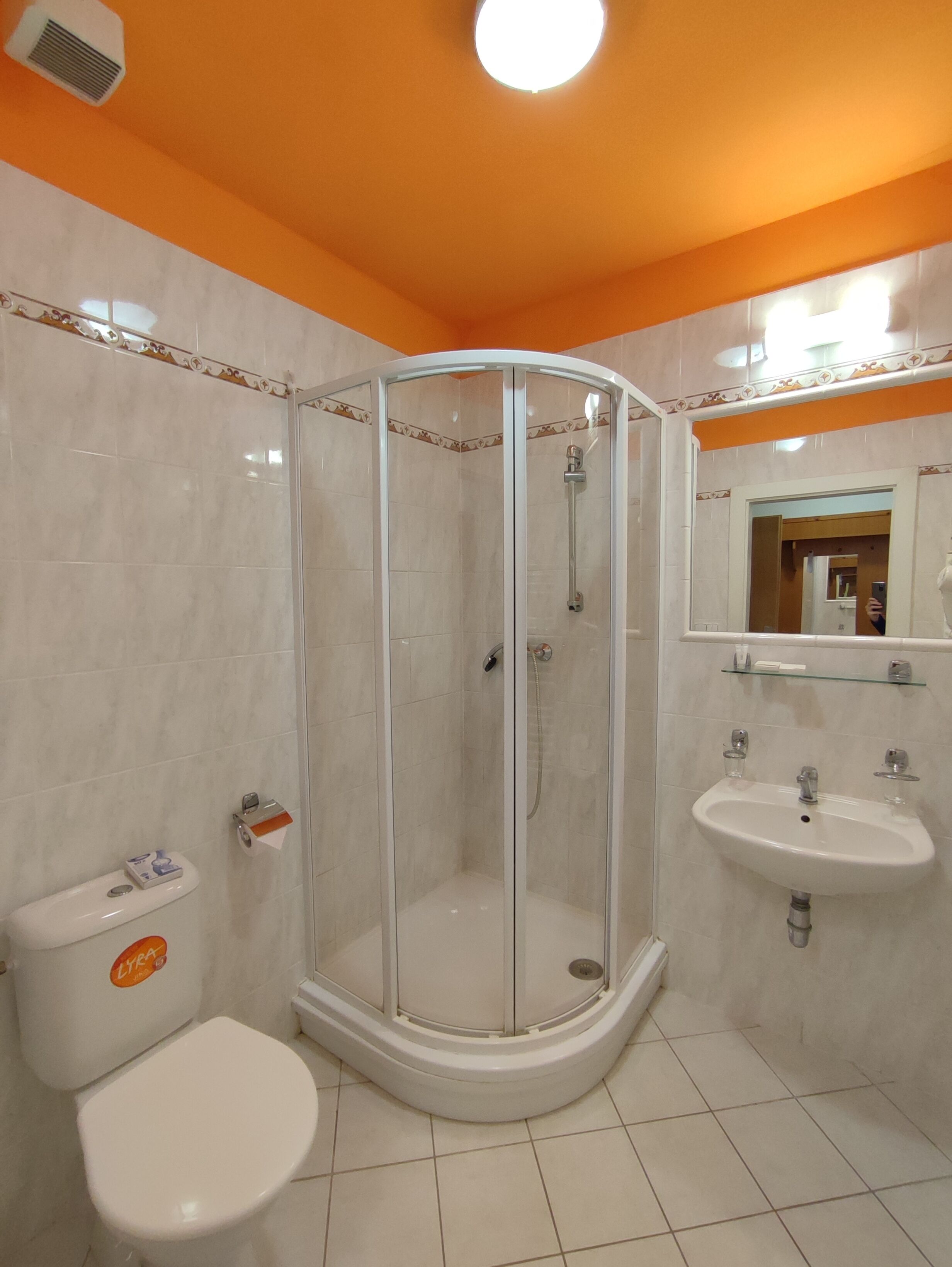 Een badkamer met een glazen douchecabine, toilet en wastafel.