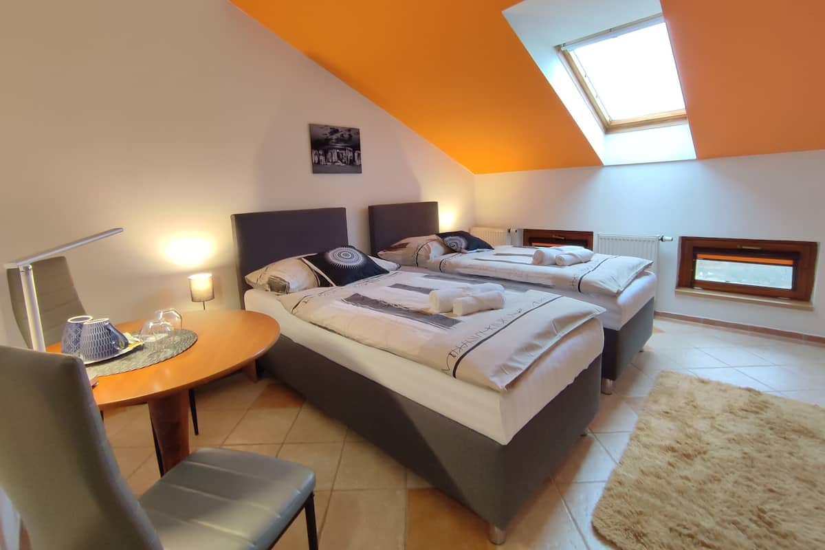 A modern bedroom with two beds, a desk, and a chair.