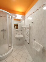 Un baño con ducha envuelta en vidrio, un lavabo y un perchero para toallas.