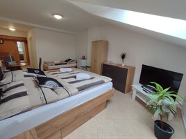 Un dormitorio moderno con una cama grande, un televisor, un escritorio y una planta en maceta.