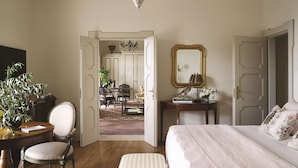 A bedroom with a bed, a bedside table, a chair, a desk, a mirror, and a chandelier. - Villa Margherita (Ravello)