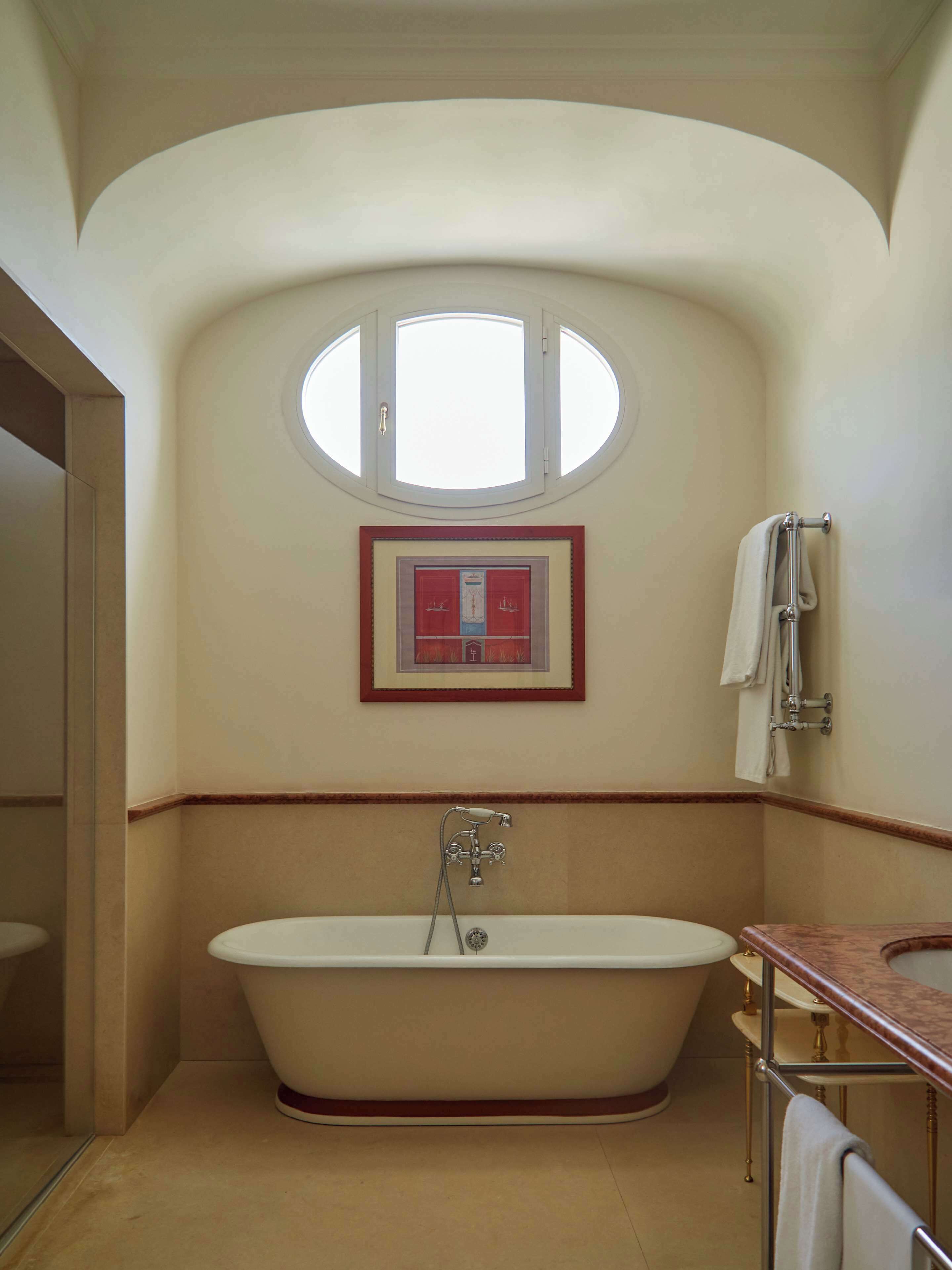 Un bagno con una vasca freestanding, una finestra e un quadro appeso al muro.