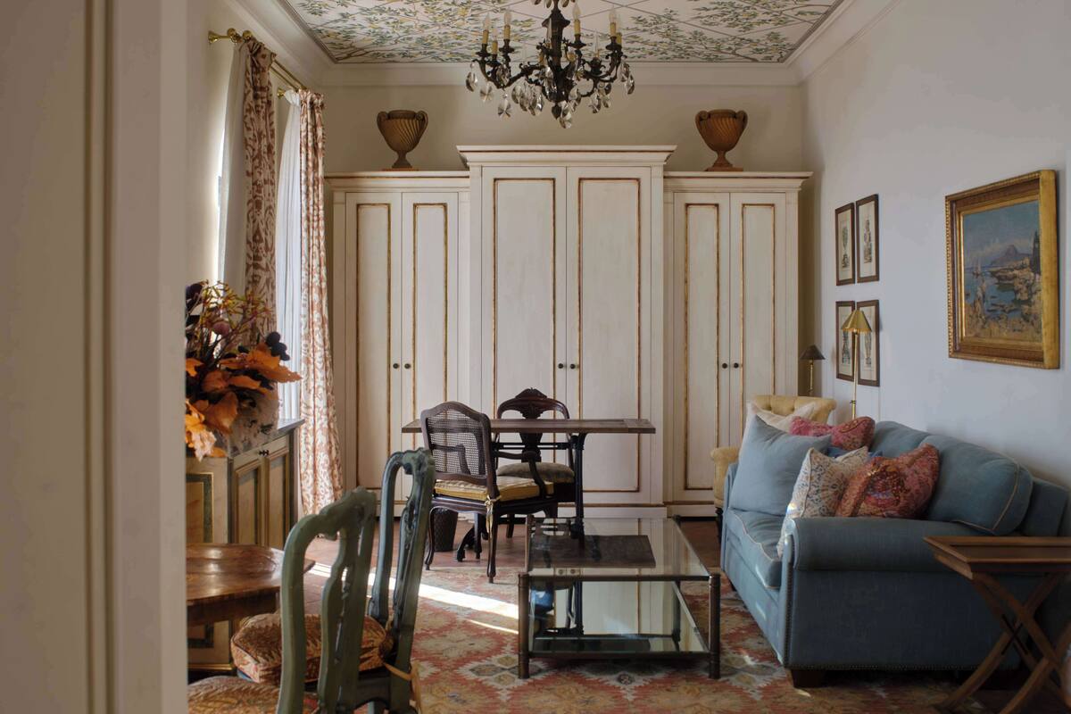 Un salon comprenant un canapé, des fauteuils, une table et un lustre.
