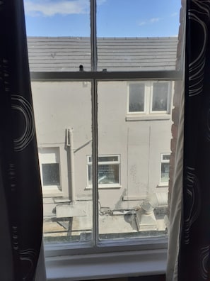 A window with a view of a building with a grey facade and a white window frame.