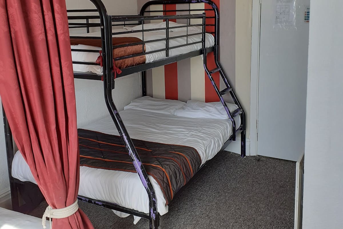 A bunk bed room with striped walls, a white door, and a red curtain.
