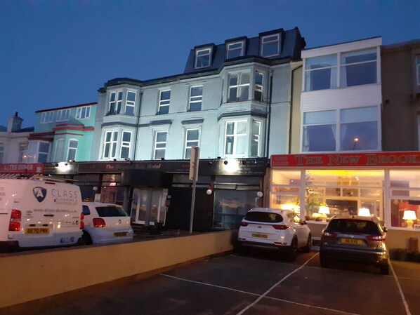 A building with multiple floors and large windows, including a ground-floor shop with a sign that reads "The New Brook Hotel".
