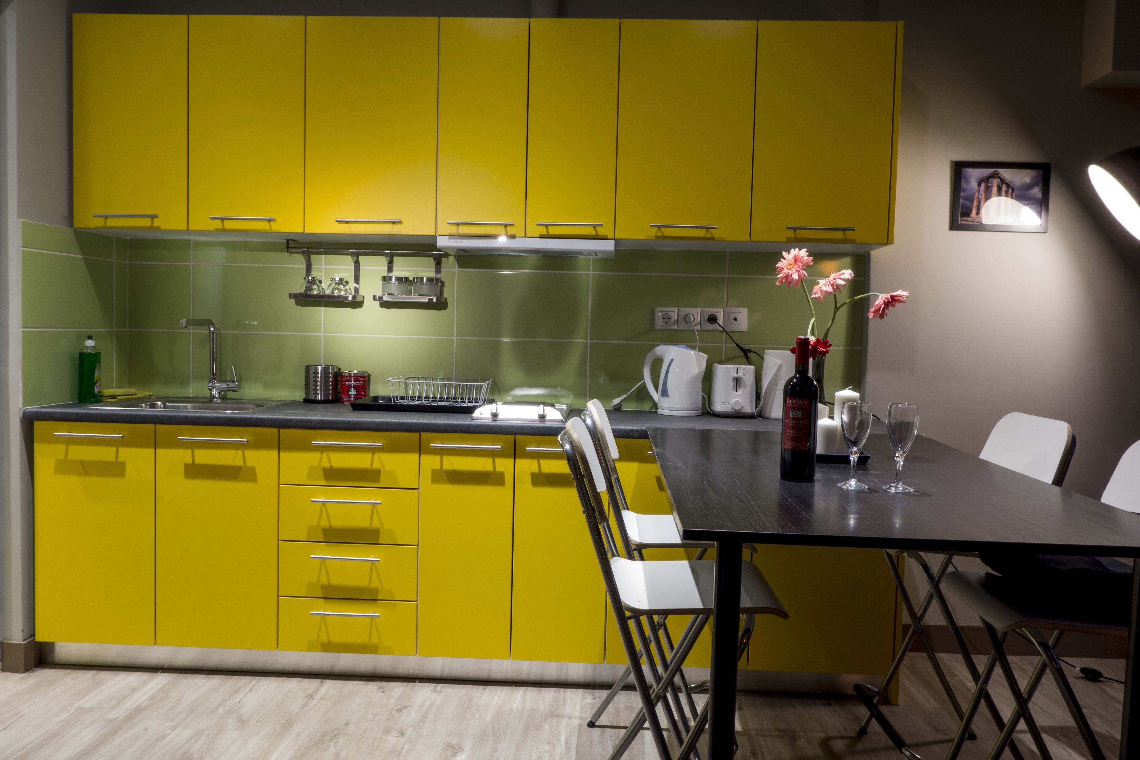 Una cocina moderna con gabinetes amarillos y una mesa para dos comensales.