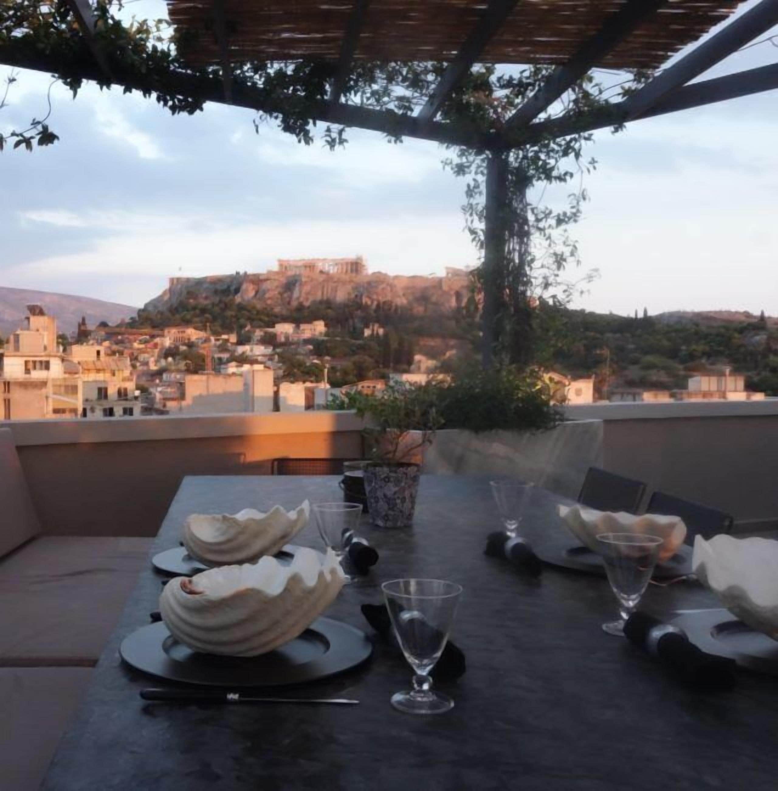 A rooftop dining area with a view of a historic building on a hill.