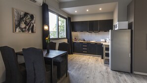 Una cucina moderna con mobili scuri, un frigorifero e un'area pranzo con tavolo e sedie.