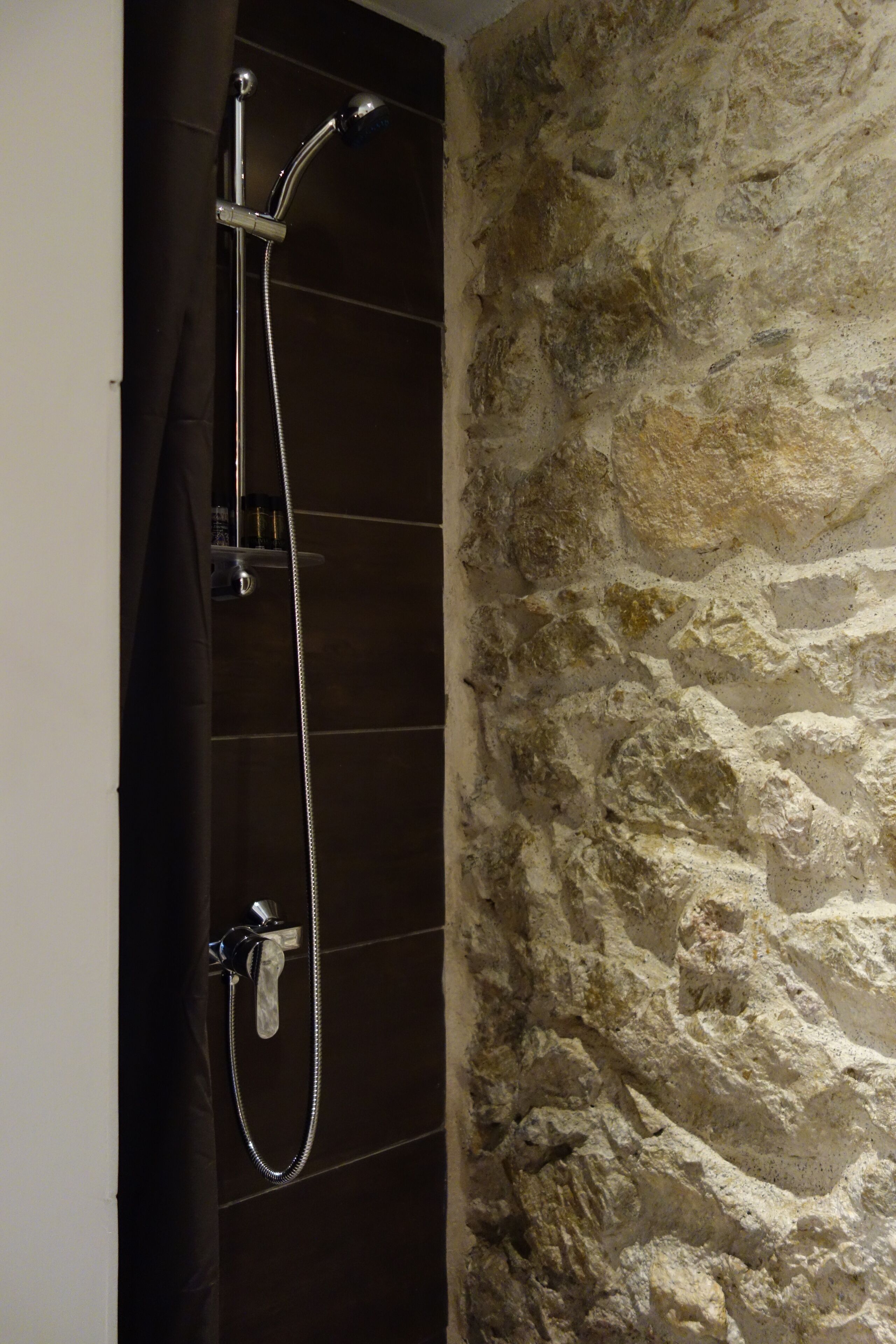 A shower with a handheld showerhead and a wall-mounted faucet.