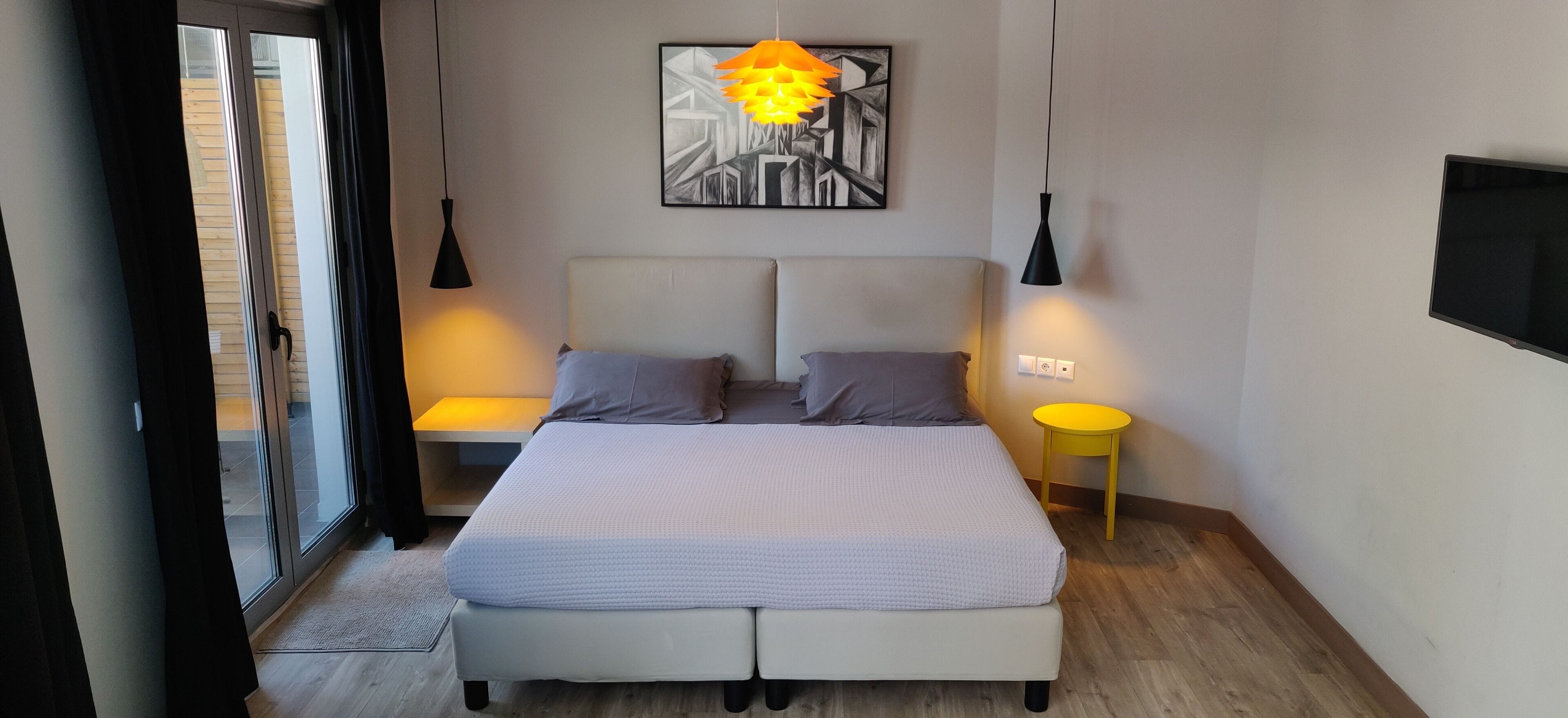 A modern bedroom with a bed, bedside tables, a wall-mounted TV, and a painting.