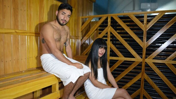 Eine Sauna mit Holzbänken und einer Metallgitterstruktur.