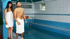 Ein Swimmingpool mit blauer Fliesenwand und Metallleiter.