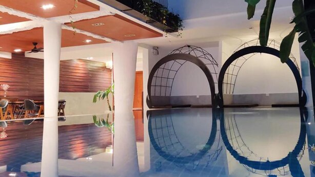 Una piscina interior de diseño moderno, con suelo de madera y techo con vigas a la vista.